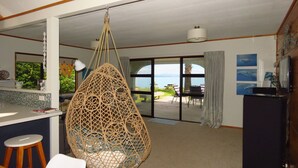 A spacious room with a hanging chair, a kitchen area, and a view of the outdoors.