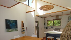 A compact kitchen with a central island, white chairs, and a dining table.