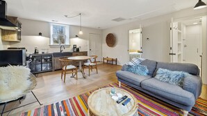 A modern living room with a grey sofa, a round coffee table, and a colorful striped rug.