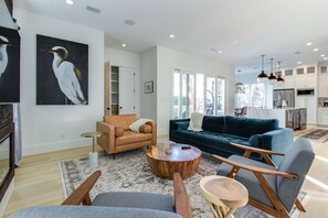 A spacious living area with a sofa, armchairs, a coffee table, and a painting of a bird.