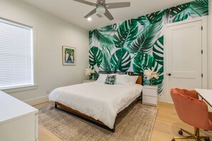 A bedroom with a bed, nightstands, a desk, a chair, a ceiling fan, and a door. - Modern 30A Grayton Beach Retreat | 5 min to beach | 4 Bikes | Huge Pool! (Santa Rosa Beach)