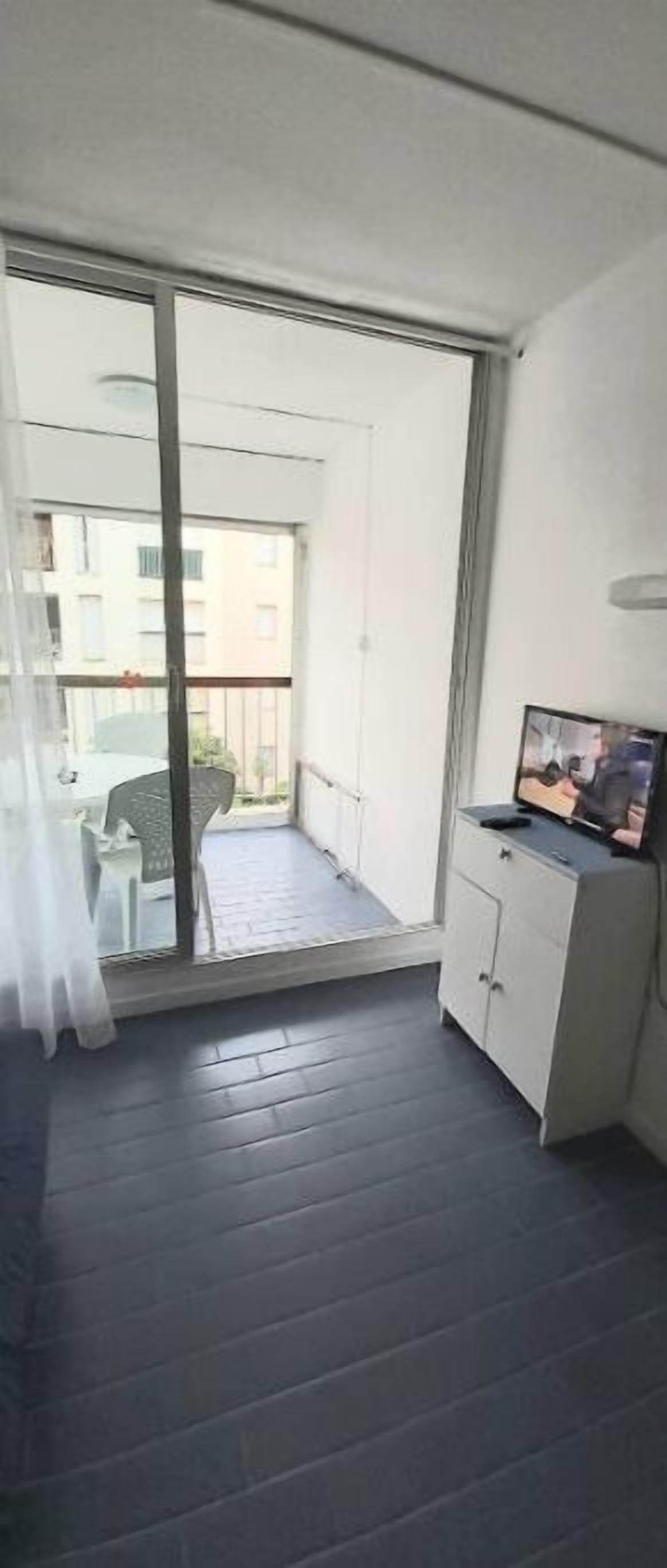 A balcony with a sliding glass door, a small table, and a television on a cabinet.