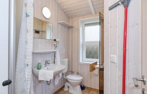 Et badeværelse med vask, toilet og bruseområde.