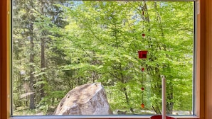 A window with a view of a forest, a large rock, and a candle holder. - Amazing Home in Mollaryd With 2 Bedrooms and Wifi (Ljung)