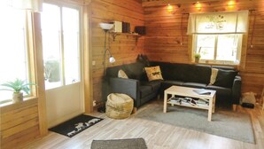 A cozy cabin interior with a wooden interior, a sofa, a coffee table, and a window with curtains. - Awesome Home in Huskvarna With 3 Bedrooms, Jacuzzi and Wifi (Huskvarna)
