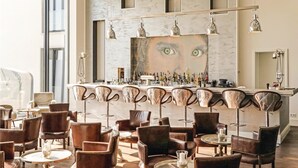 Een bar met een marmeren toonbank, meerdere barstoelen en een grote spiegel.