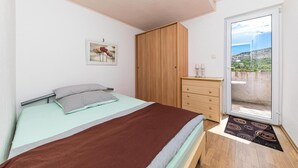 A bedroom with a bed, a wooden wardrobe, a dresser, a framed picture, and a balcony with a view. - Amazing Apartment in Labin With Outdoor Swimming Pool, Wifi and 4 Bedrooms (Prgomet)