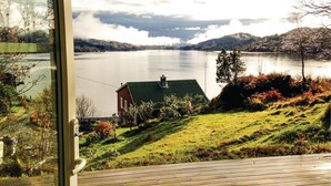 A lakeside view from a window overlooking a house with a green roof, surrounded by lush greenery and hills. - Stunning Home in Seim With 2 Bedrooms and Wifi (Alver)