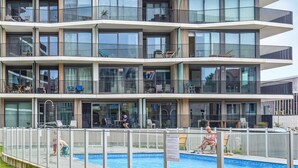 A multi-story building with a swimming pool, balconies with outdoor furniture, and a clear view of the surrounding area. - Residentie Crystal Ref. 84 (Ostend)