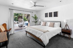 A bedroom with a bed, bedside tables, a ceiling fan, and a view through a sliding glass door.