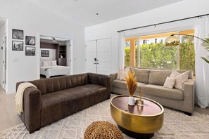 A modern living room with a brown sofa, a beige sofa, and a round coffee table. - Palm Springs Luxury: Pool, Hot Tub & Downtown Access (Palm Springs)