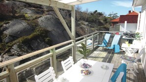 An outdoor deck with a table set for two, chairs, and a potted plant. - Beautiful Apartment in Kungshamn With 3 Bedrooms and Wifi (Kungshamn)