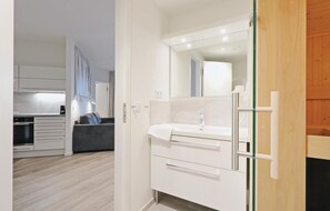 A modern bathroom with a white vanity, a large mirror, and a glass shower enclosure. - Awesome Apartment in Lübeck Travemünde With 2 Bedrooms, Sauna and Wifi (Lübeck)