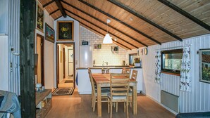 Eine gemütliche Küche mit Holzbalken, einem Essbereich mit Tisch und Stühlen sowie einem Blick ins Freie durch ein Fenster.