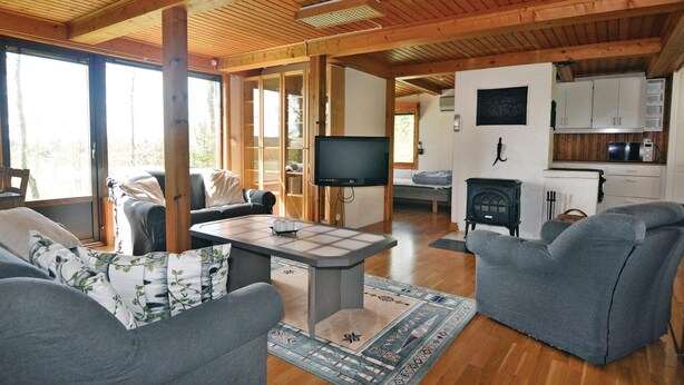 Een gezellig cabin interieur met een zithoek, inclusief een bank, een salontafel en een televisie. Er is ook een keuken met kasten en een fornuis.