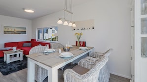 Un comedor con mesa de madera, sillas de mimbre y sofá rojo.