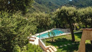 Ein Poolbereich mit Stufen, umgeben von üppiger Vegetation und Bergen im Hintergrund.