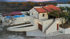 A stone villa with a swimming pool, a red-roofed structure, and a view of mountains. - Stone House Captivating Villa in Pridraga, Zadar (Novigrad)