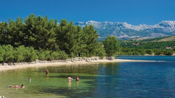 A clear lake with people swimming, surrounded by trees and mountains in the background. - Stone House Captivating Villa in Pridraga, Zadar (Novigrad)