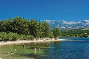 A clear lake with people swimming, surrounded by trees and mountains in the background. - Stone House Captivating Villa in Pridraga, Zadar (Novigrad)