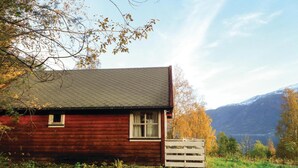 Une petite cabane en bois rouge, avec un toit en pente, une petite fenêtre et une clôture blanche devant.