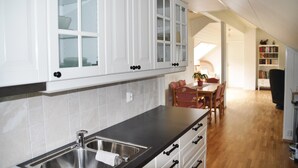 A kitchen with white cabinets, a black countertop, and a wooden dining table with chairs. - Nice Apartment in Fitjar With 2 Bedrooms and Wifi (Fitjar)