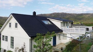 A house with a steeply pitched roof, a small balcony, and a view of hills in the background. - Nice Apartment in Fitjar With 2 Bedrooms and Wifi (Fitjar)