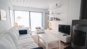 A modern living room with a white sofa, a flat-screen TV, a coffee table, and a fireplace. - Awesome Home in Burgsvik With 3 Bedrooms and Wifi (Burgsvik)