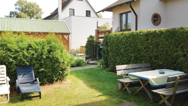 A backyard with a wooden table and chairs, a wooden bench, and a hedge. - Amazing Apartment in Koserow With 2 Bedrooms and Internet (Koserow)