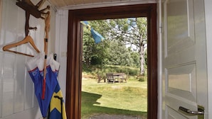 Una puerta que da a un espacio al aire libre con césped, un banco y una bandera.