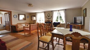Un salón acogedor con comedor, muebles de madera, un televisor y un papel tapiz estampado.