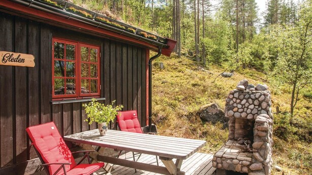 A wooden cabin with a red window, a table with chairs, and a stone fireplace. - Beautiful Home in Rendalen With 4 Bedrooms (Rendalen)