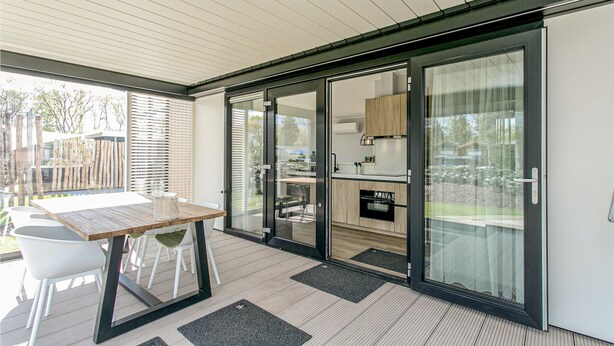 Una cocina moderna con puertas de cristal correderas, una mesa de madera y vistas al exterior.
