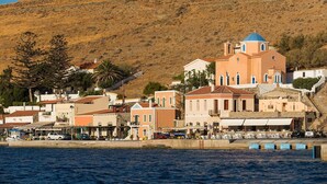 A coastal town with a prominent church featuring a blue dome, surrounded by colorful buildings and a hillside backdrop. - Charming two Bedroom Fisherman's House on Kea (Kea)