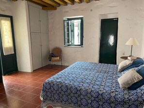 A bedroom with a bed, a chair, a window, and a door. - Charming two Bedroom Fisherman's House on Kea (Kea)