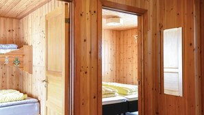 A wooden cabin room with a bed, a bench, and a door leading to another room. - Amazing Home in Sysslebäck With 2 Bedrooms and Wifi (Sysslebäck)