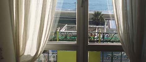 A balcony with a view of the sea, featuring a metal railing and a green wall.
