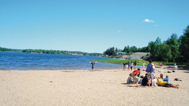 Ein Strand mit Menschen, die sich entspannen und am Ufer entlanggehen.