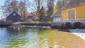 En vy över en flod med ett trähus och en byggnad av sten.