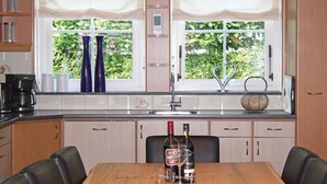 Une cuisine avec une table à manger, deux bouteilles de vin et une machine à café.