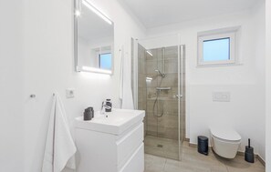 A modern bathroom with a glass-enclosed shower, a white vanity with a mirror, and a toilet. - Amazing Apartment in Lembruch/dümmer See With 2 Bedrooms, Wifi and Indoor Swimming Pool (Lembruch)