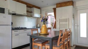 A kitchen with white cabinets, a stove, and a dining table with chairs.