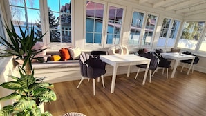 A spacious room with large windows, a wooden floor, and a seating area with a plant and ottomans. - Maly Sopot Boutique (Ilawa)