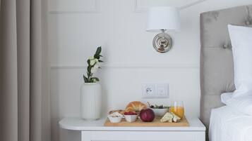 Une chambre d’hôtel bien rangée, avec un lit, une table de chevet dotée d’une lampe et une petite plante.