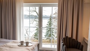 A bedroom with a bed, a chair, and a window with a view of trees and mountains. - Maly Sopot Boutique (Ilawa)