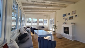 A spacious living room with a long grey sofa, a blue chair, and a white fireplace. - Maly Sopot Boutique (Ilawa)