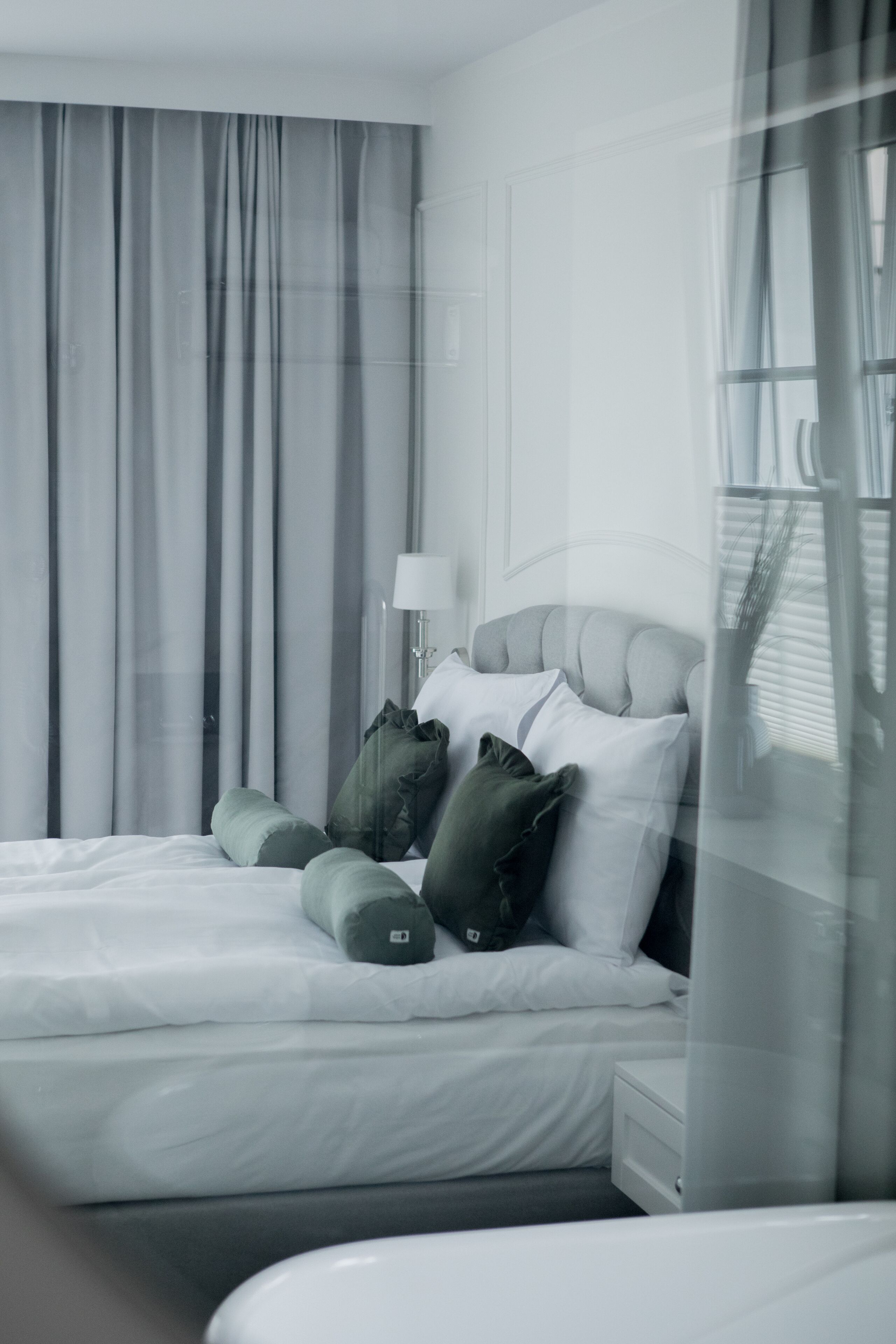 A modern hotel room with a large bed, a bedside table, and a lamp.
