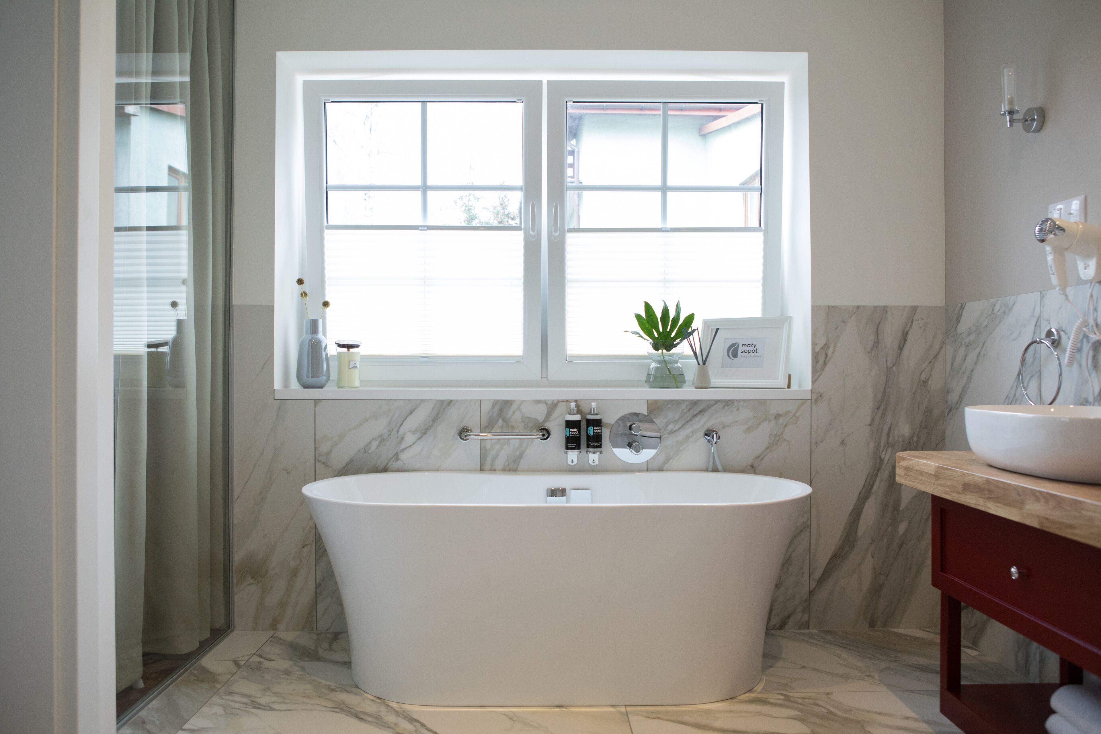 Une salle de bain moderne avec une baignoire sur pieds, une fenêtre au-dessus du lavabo et un pare-feu en marbre.