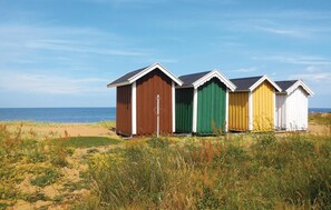 Una hilera de cabañas de playa, con una playa arenosa y el océano al fondo.