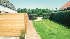 A well-maintained backyard with a paved pathway, neatly trimmed grass, and a wooden fence. - Golf 3 (Middelkerke)